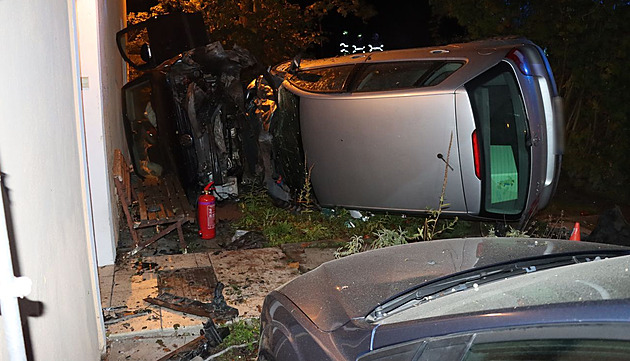 Řidič se dvěma promile nezvládl zatáčku, narazil do zaparkovaného auta a domu